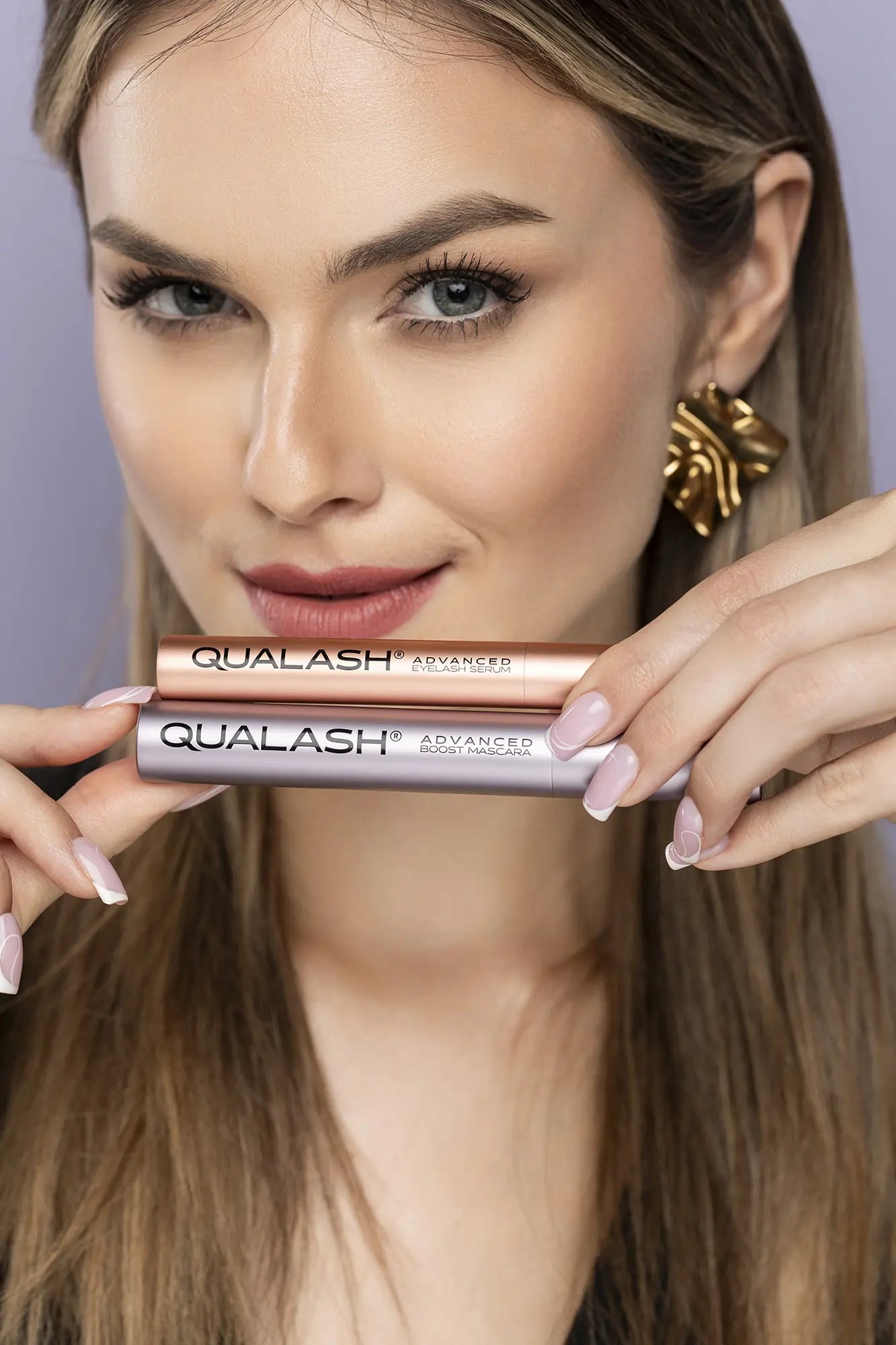 Close-up of hands holding QUALASH Advanced Eyelash Serum and Mascara Volume Max