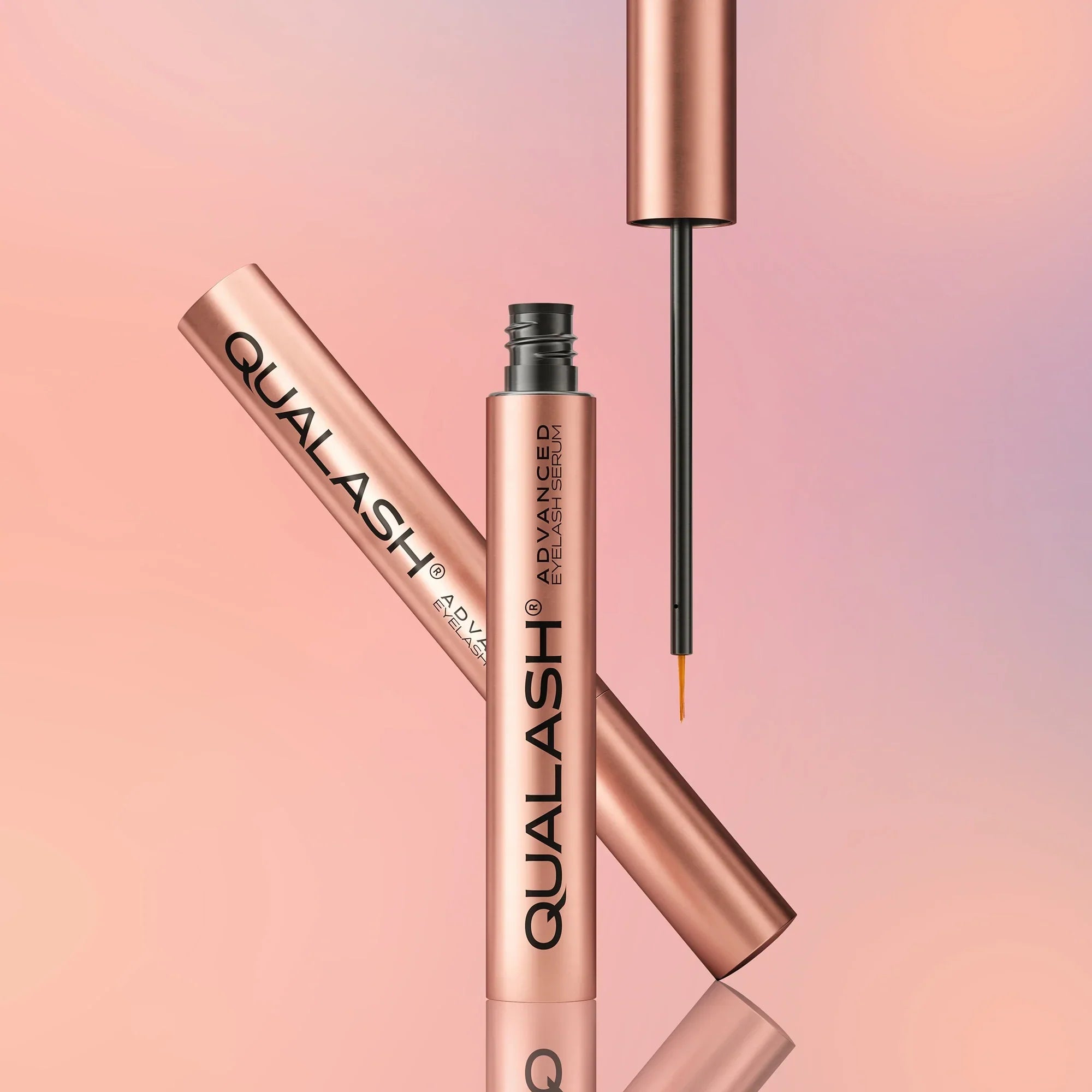 QUALASH Advanced Eyelash Serum in rose gold packaging on a pastel background