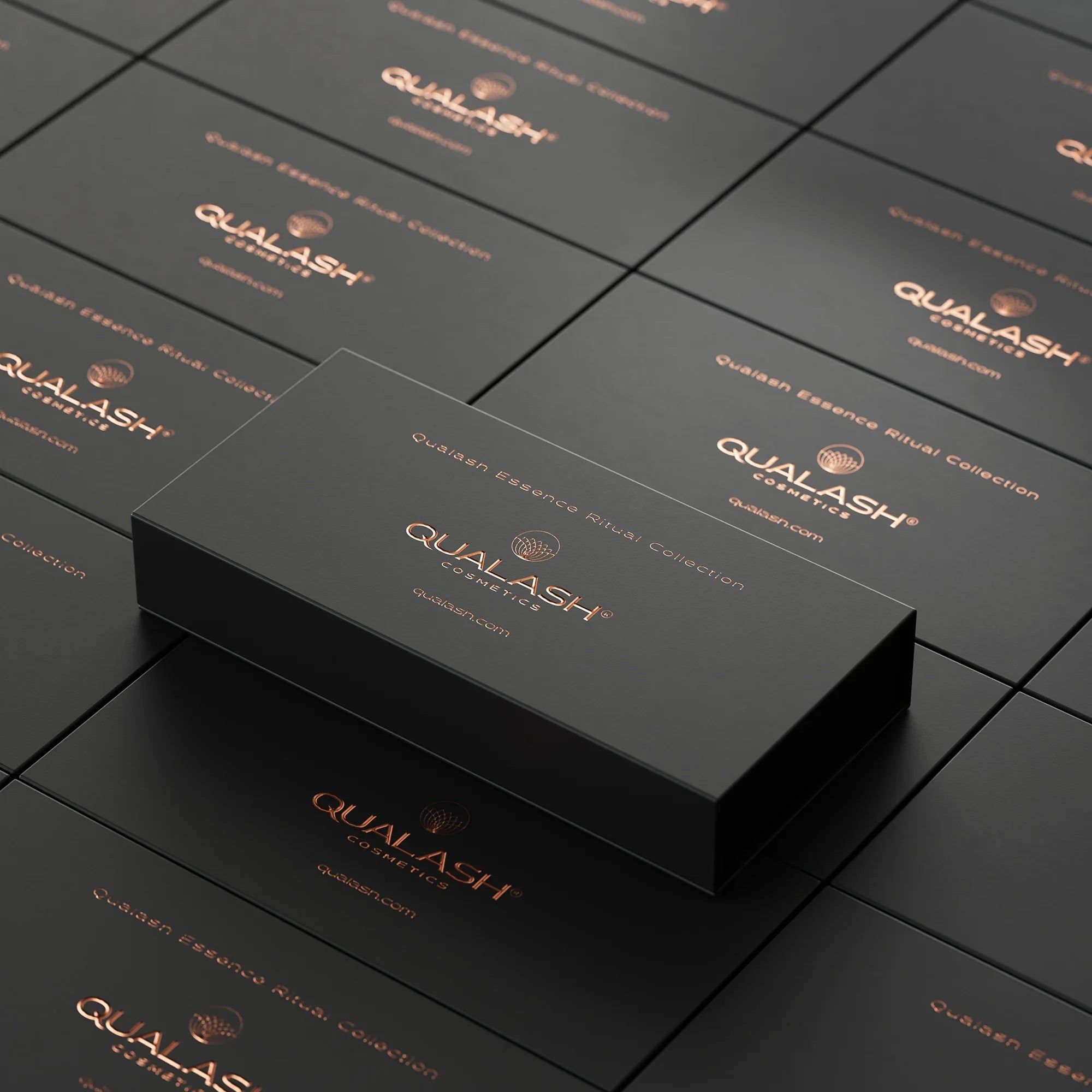 Closed QUALASH Essence Ritual Collection box displayed on a stack of identical packaging – luxury branding.