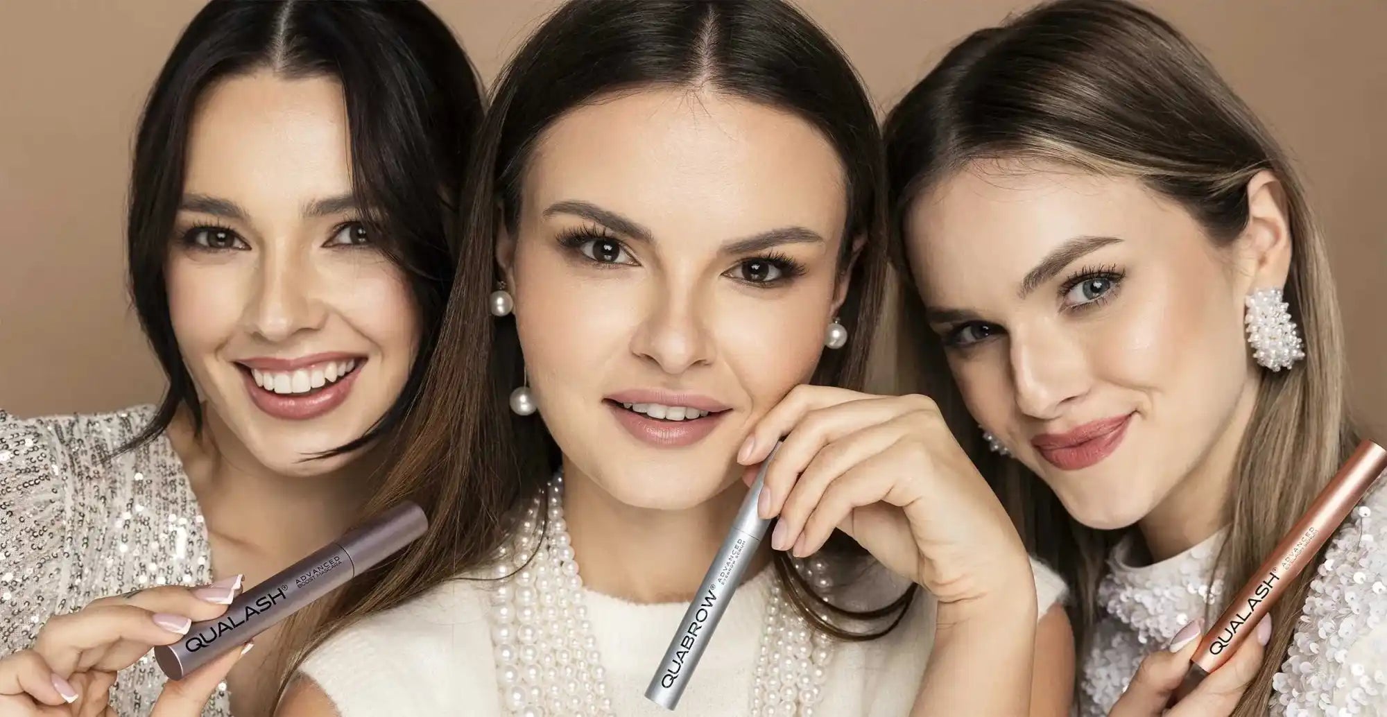Three smiling women holding Qualash and Quabrow eyelash and eyebrow serums — premium beauty photo showcasing the product collection on a clean background.