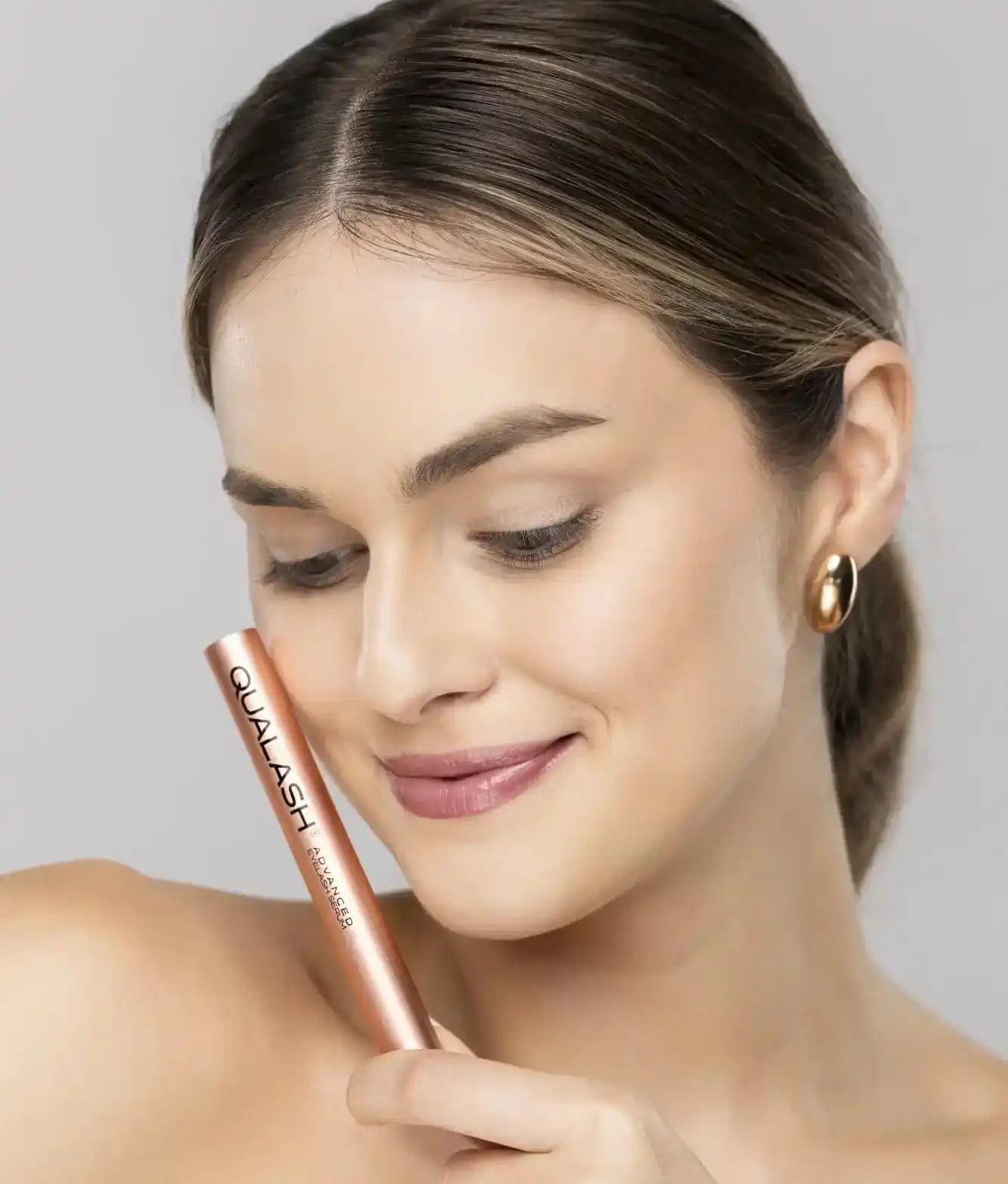 A woman holding a tube of mascara.