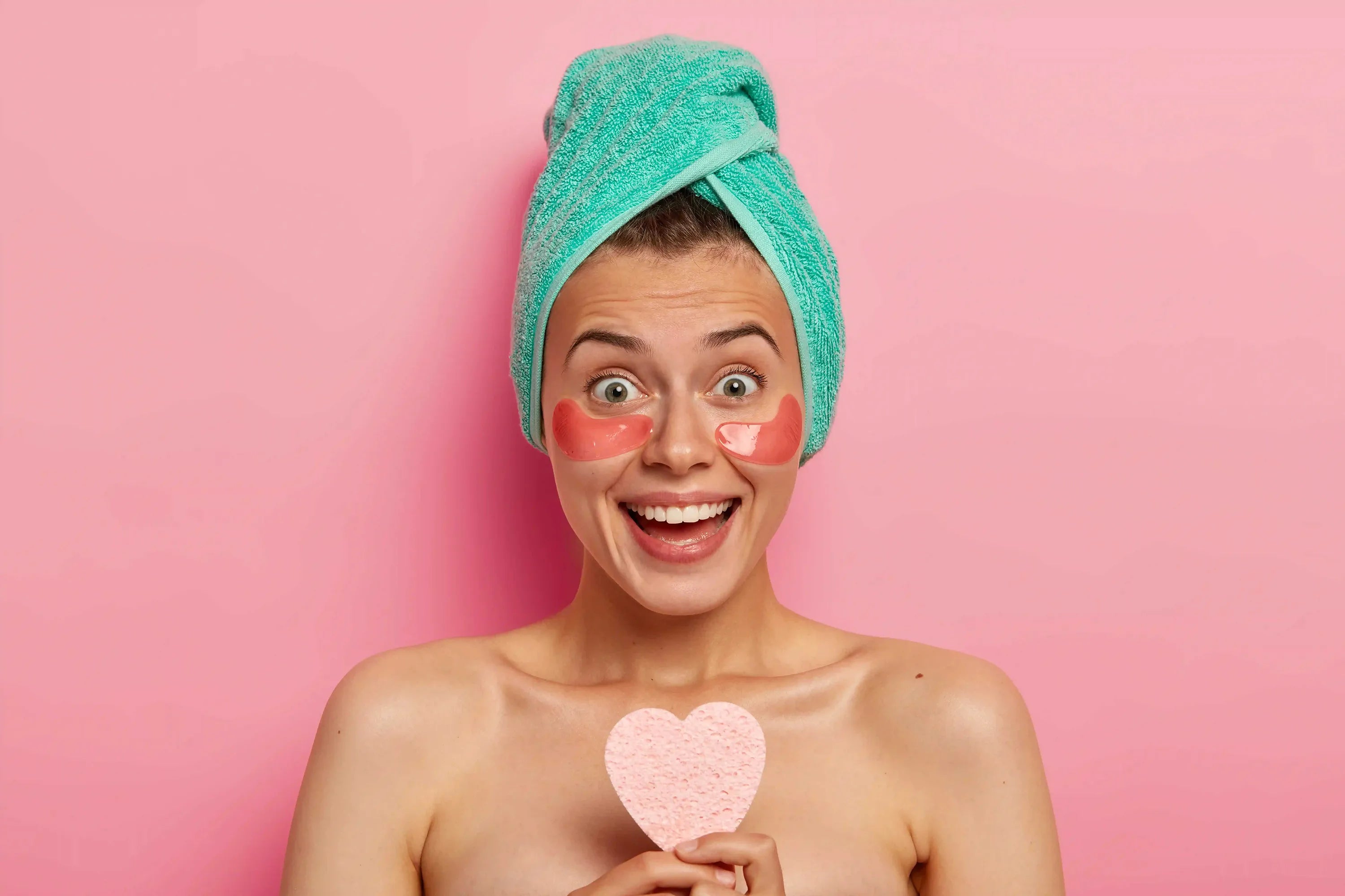 Femme avec des patchs sous les yeux et un turban en serviette souriant pendant sa routine de soins de la peau