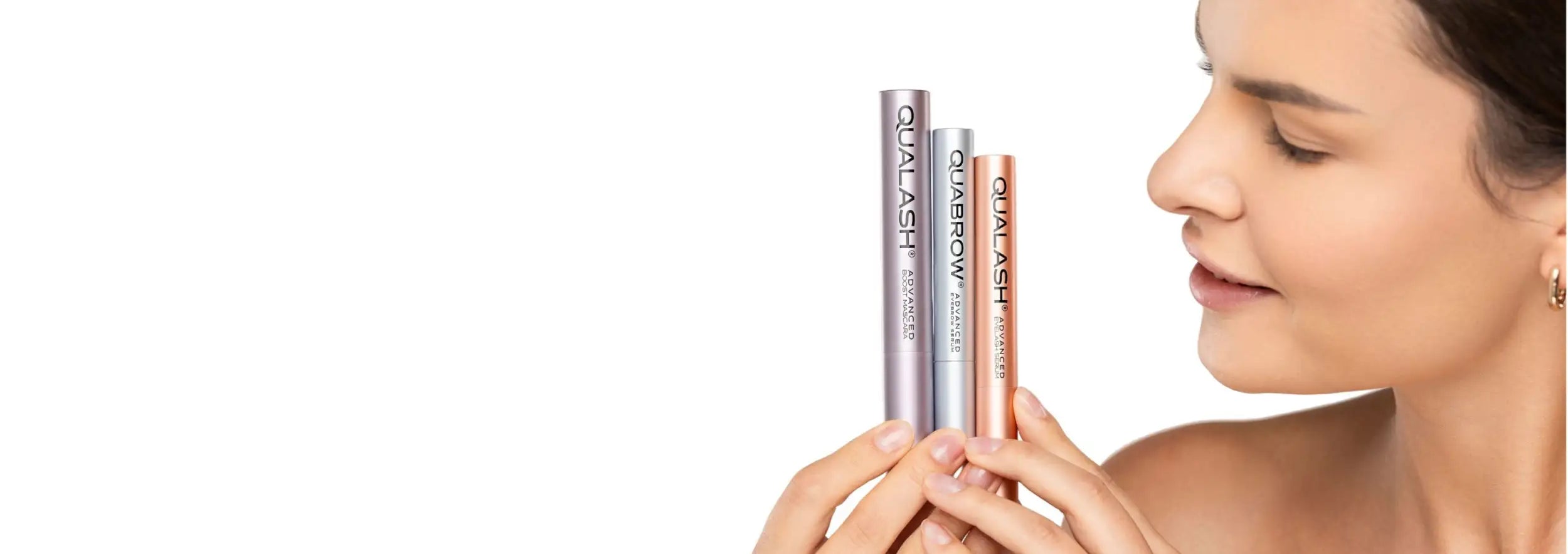 Three slender, metallic-tipped applicators with ’qua lash’ branding in silver and rose gold hues.